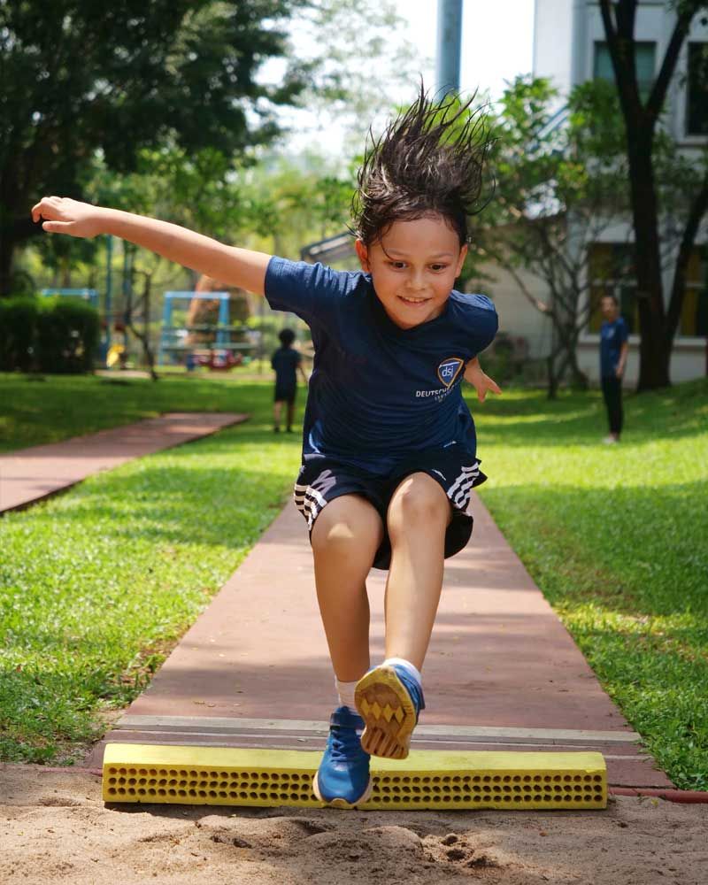 A young boy is jumping in the air on a track.