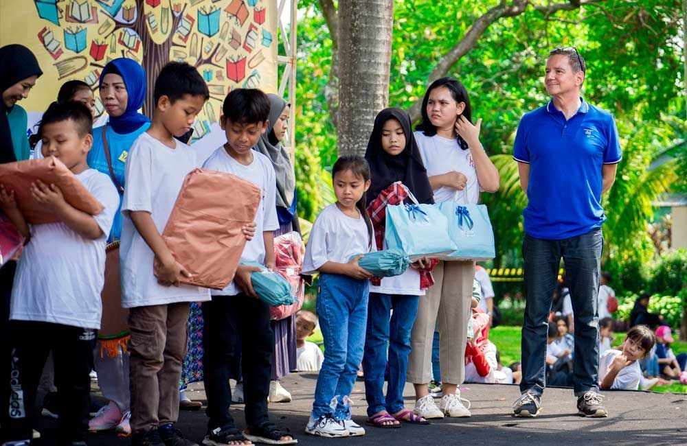 A group of children standing next to each other holding gifts.