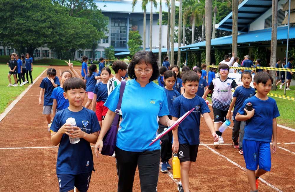 A woman is walking with a group of children on a track.