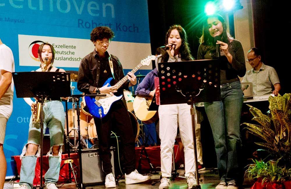 A group of people are playing instruments on a stage in front of a sign that says beethoven