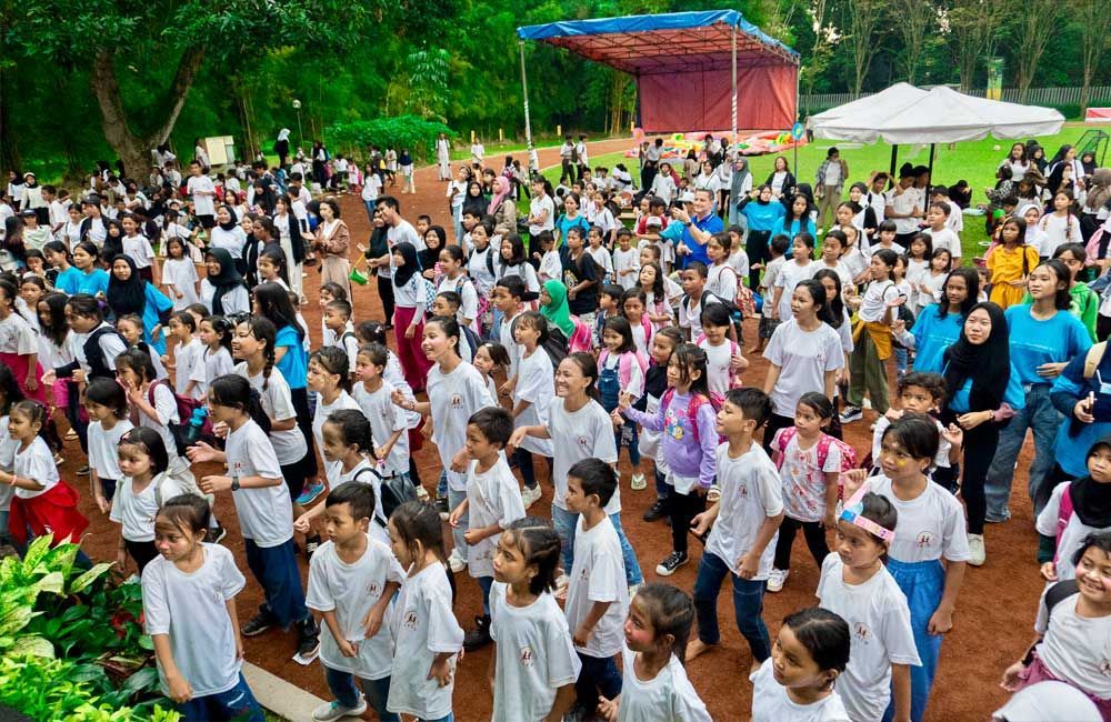 A large group of children are dancing in a park.