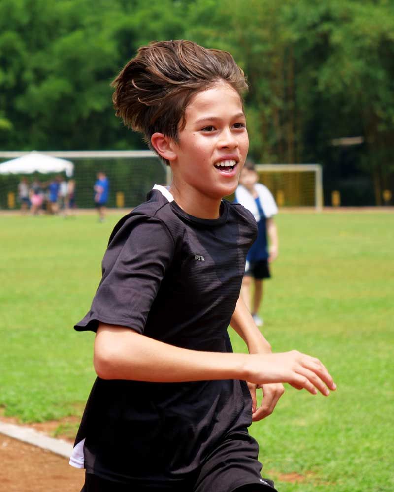 A young boy in a black shirt is running on a field