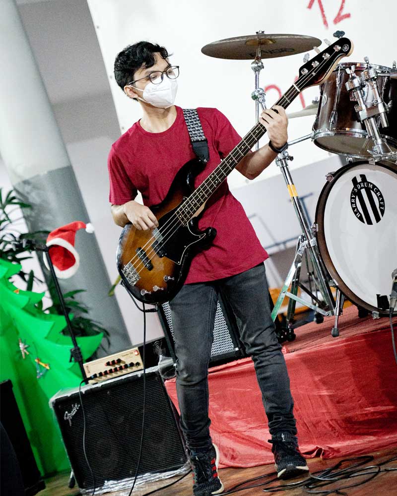 A man wearing a mask is playing a bass guitar on a stage.