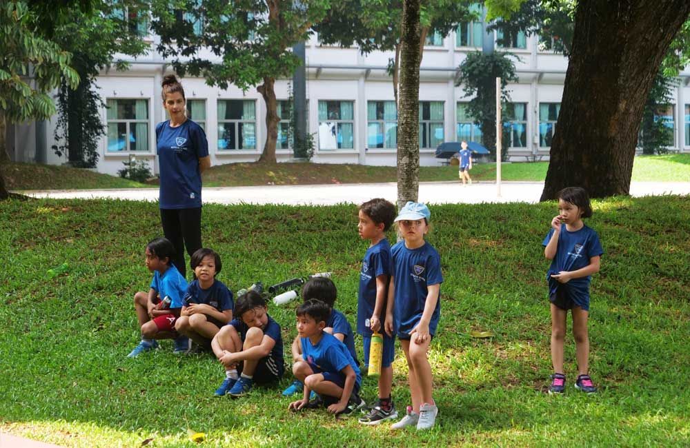A group of children are sitting on the grass in a park.