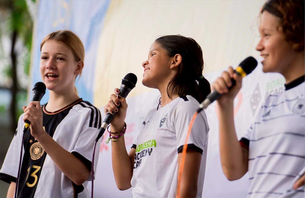 A group of young girls are singing into microphones.