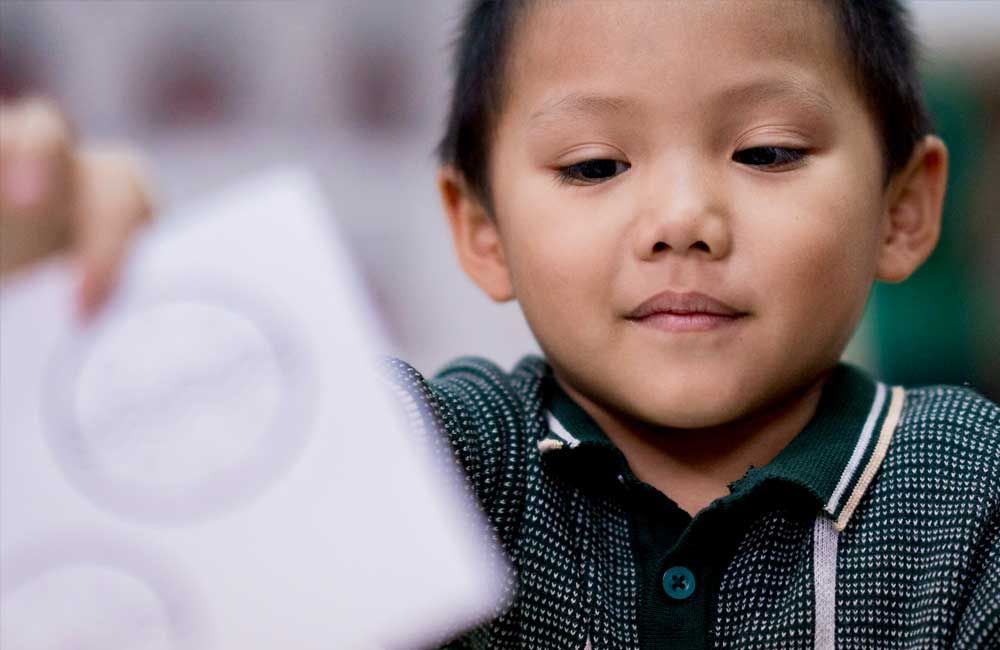A young boy is holding a piece of paper in his hand.