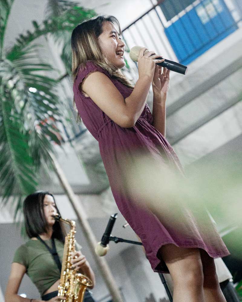 A woman is singing into a microphone while another woman plays a saxophone.