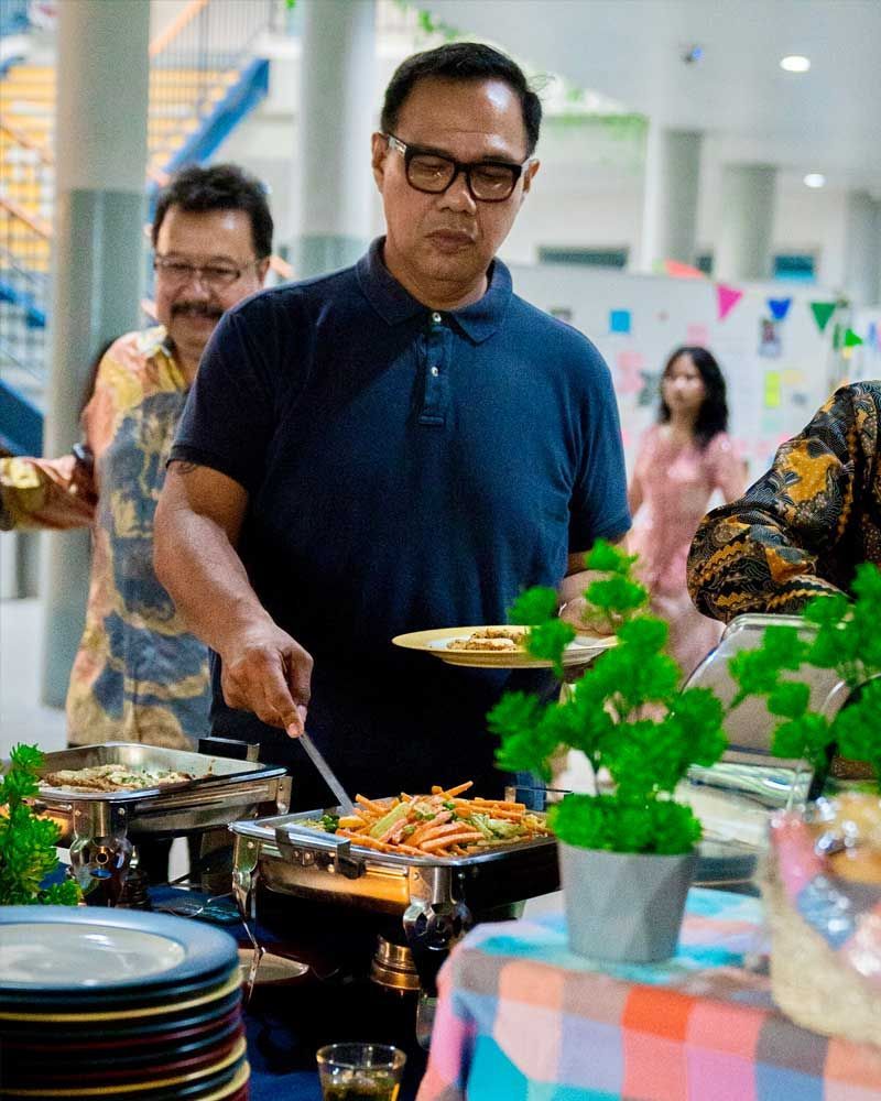A man is serving food at a buffet table.