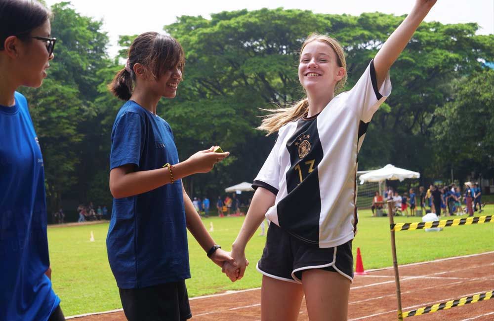 A group of young girls are holding hands on a track