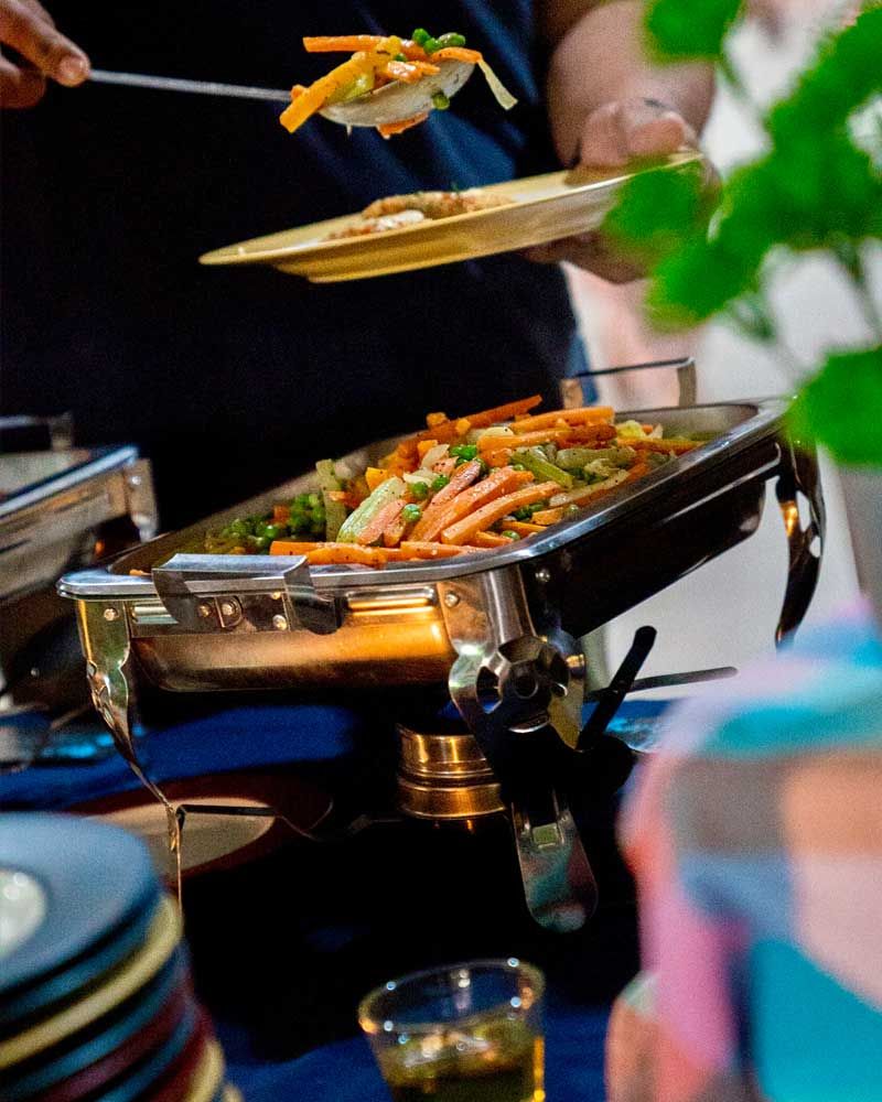 A person is taking a plate of food from a buffet