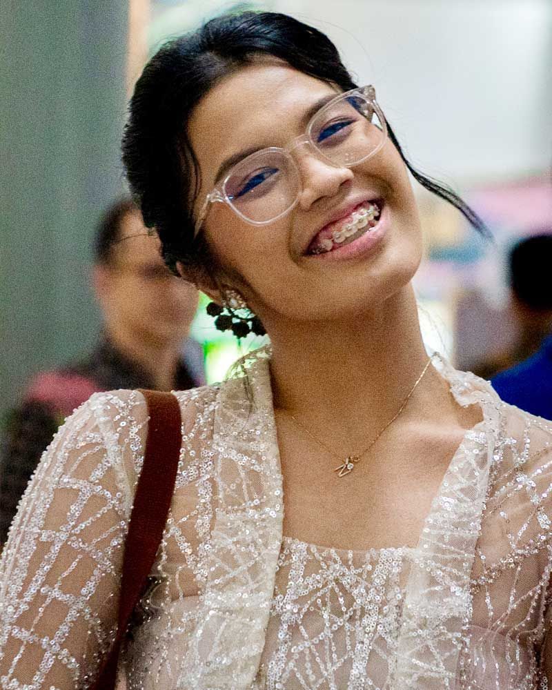 A woman wearing glasses and a white top is smiling
