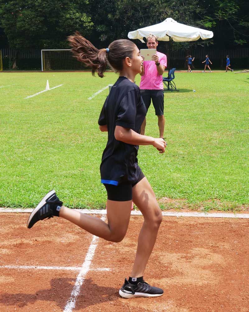 A girl in a black shirt is running on a track