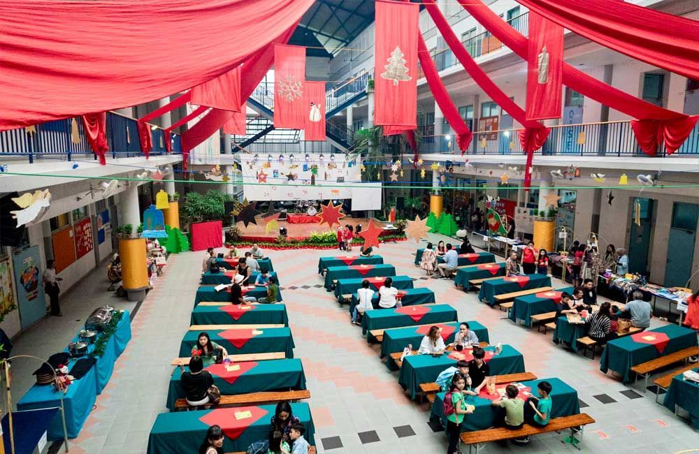 A group of people are sitting at tables in a large room decorated for christmas.