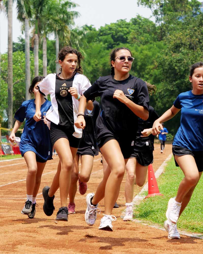 A group of young girls are running on a track.