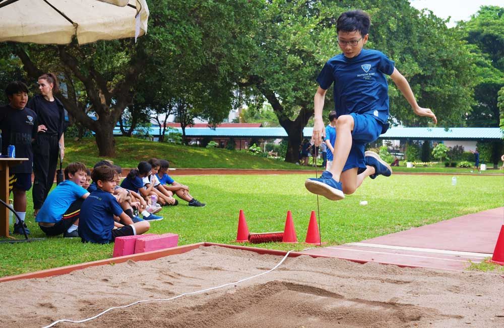 A young boy is jumping in the air while a group of children watch.