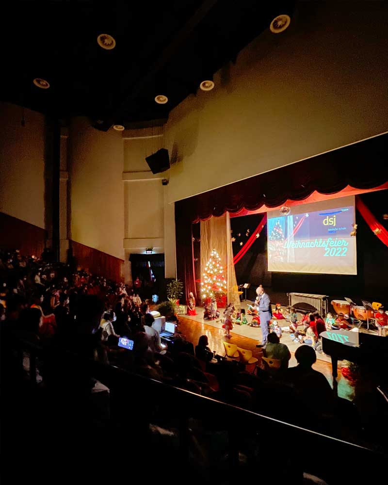 A group of people are sitting in an auditorium watching a christmas concert