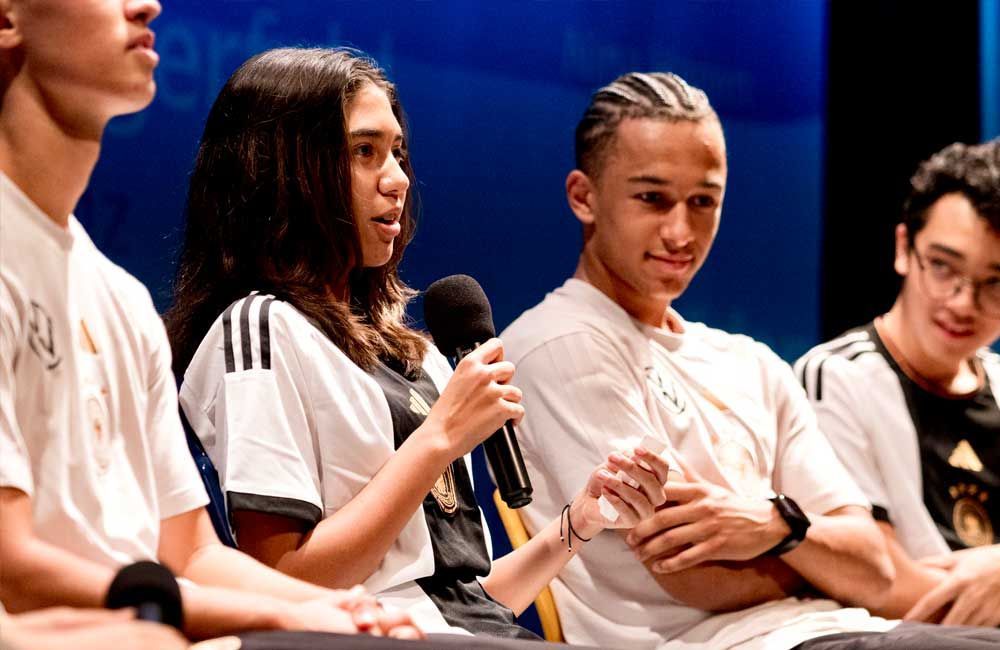 A group of young people are sitting in front of a microphone.