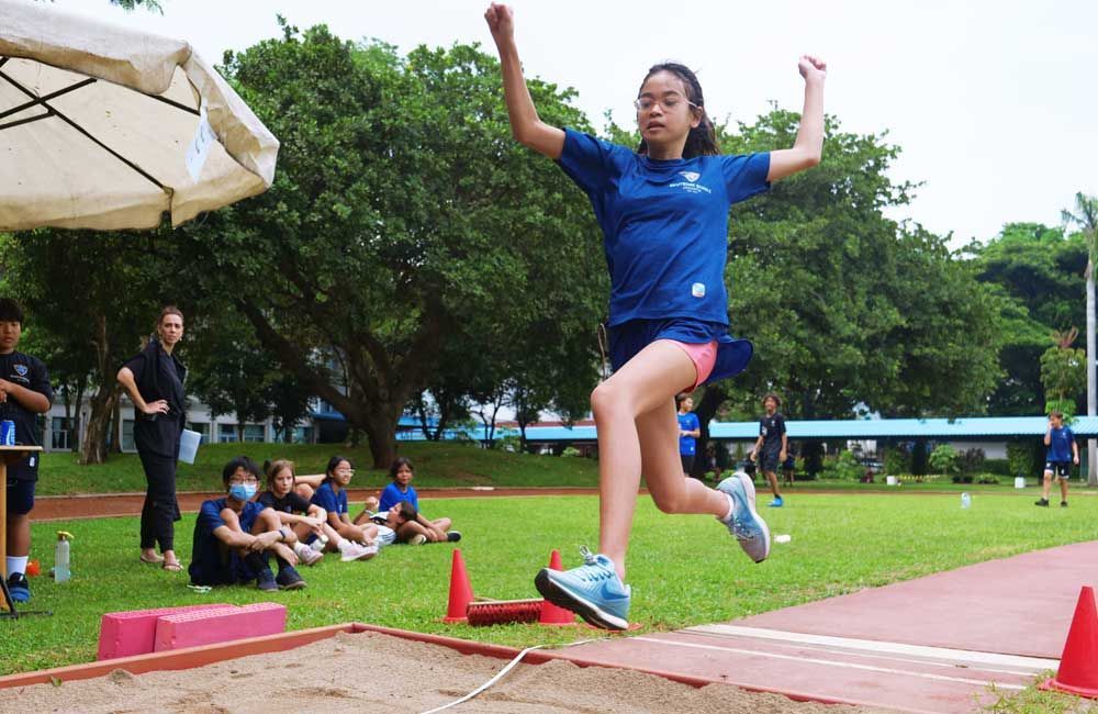 A girl in a blue shirt is jumping in the air