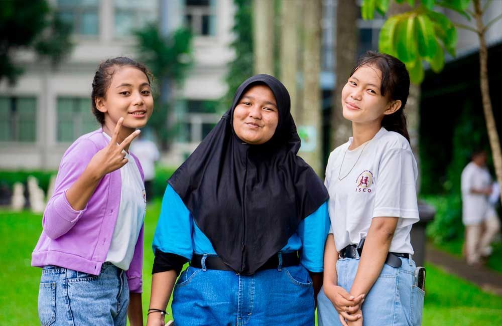 Three young women are posing for a picture in a park.