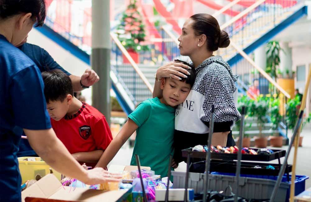 A woman hugs a young boy while she gently holds his head at an event