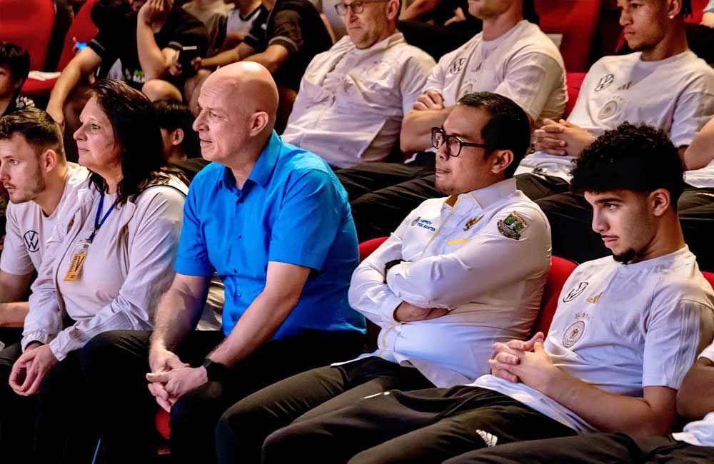 A group of people are sitting in a theater watching a presentation.
