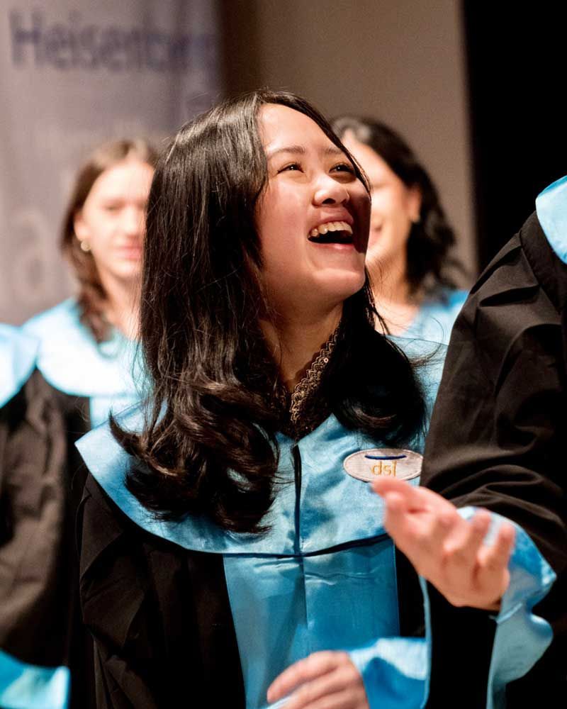 A woman in a graduation cap and gown is laughing