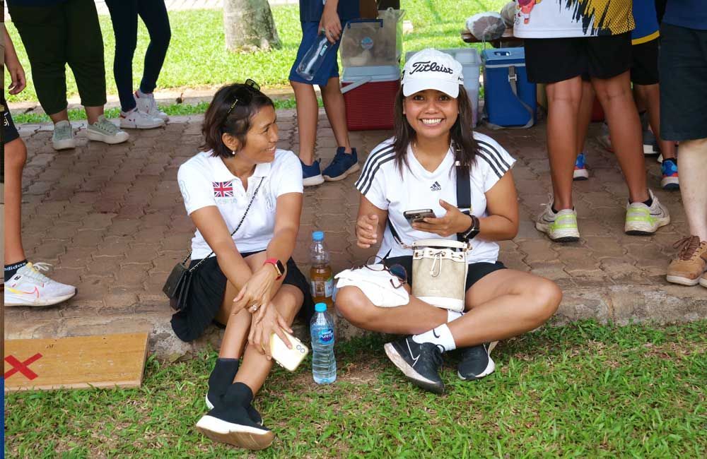 Two women are sitting on the grass with their legs crossed.