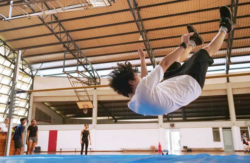 A man is doing a trick on a trampoline in a gym.