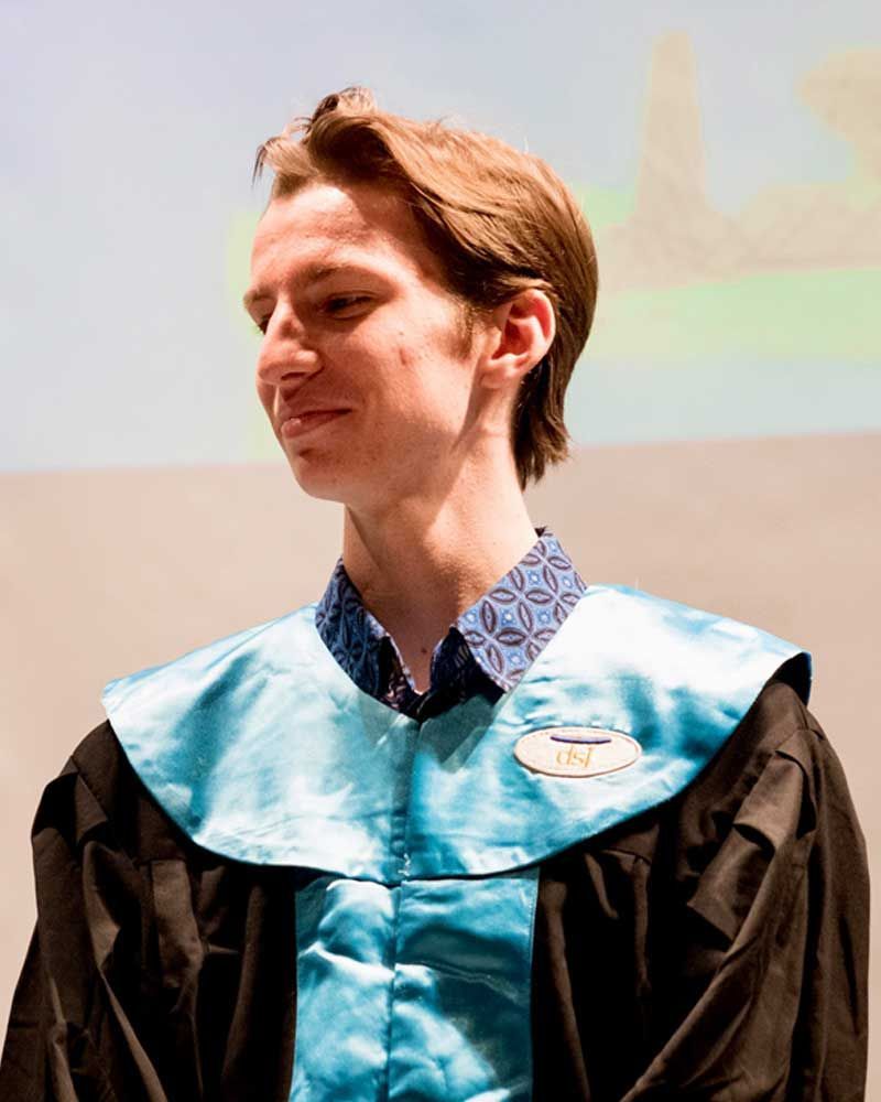 A man in a graduation cap and gown with a badge that says ' tnt ' on it