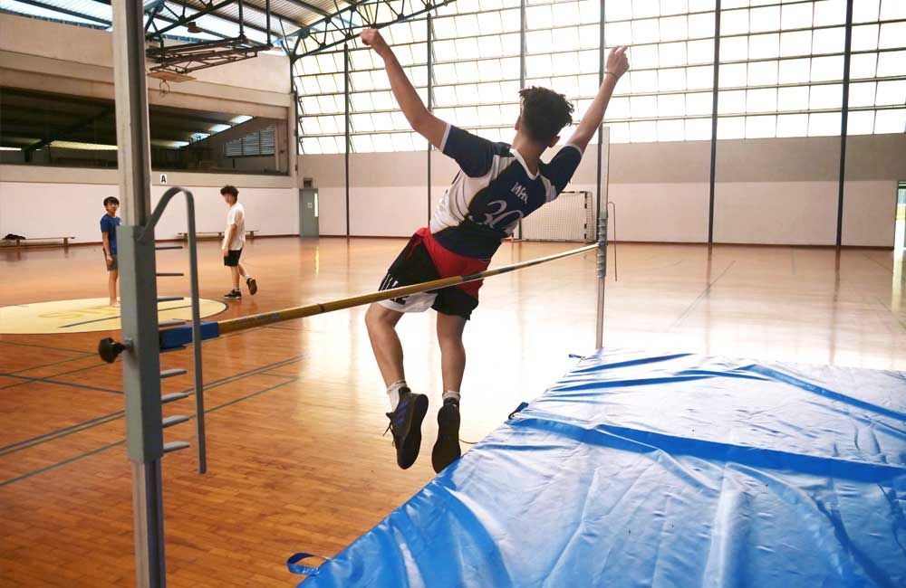 A young man is jumping over a rope in a gym.