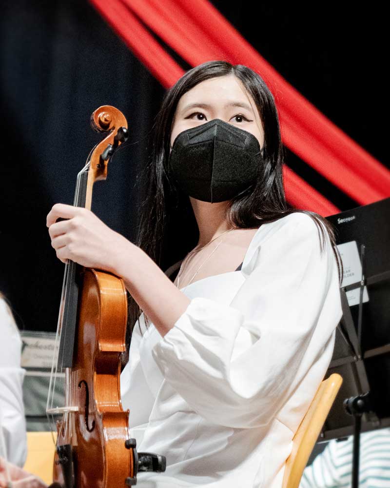 A woman wearing a mask is playing a violin