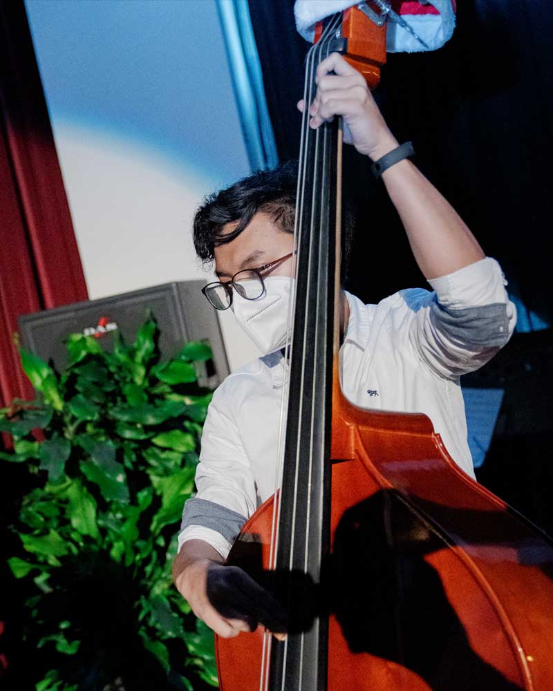 A man wearing a mask is playing a double bass