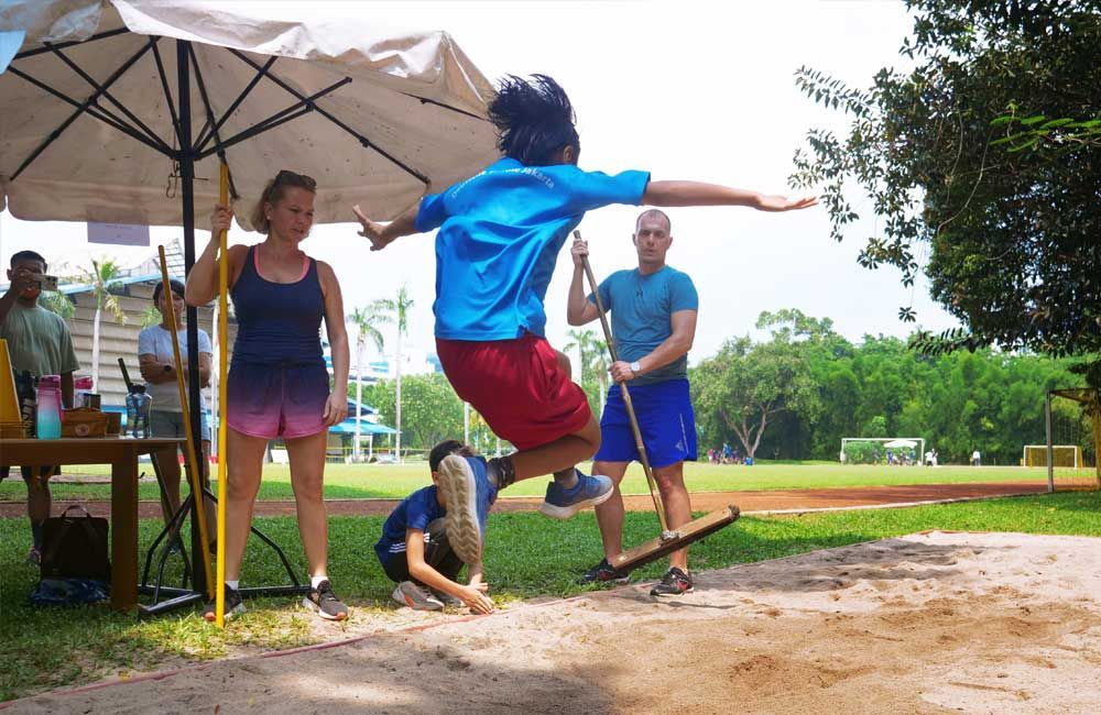 A person is jumping in the air while a group of people watch.