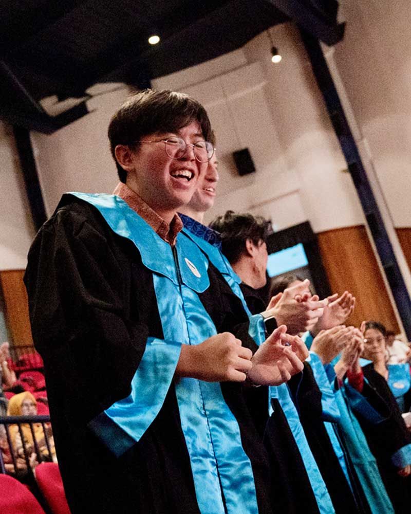 A group of people in graduation gowns are clapping their hands