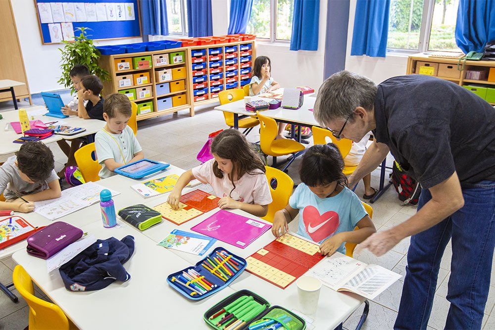 A teacher is helping a group of children in a classroom.