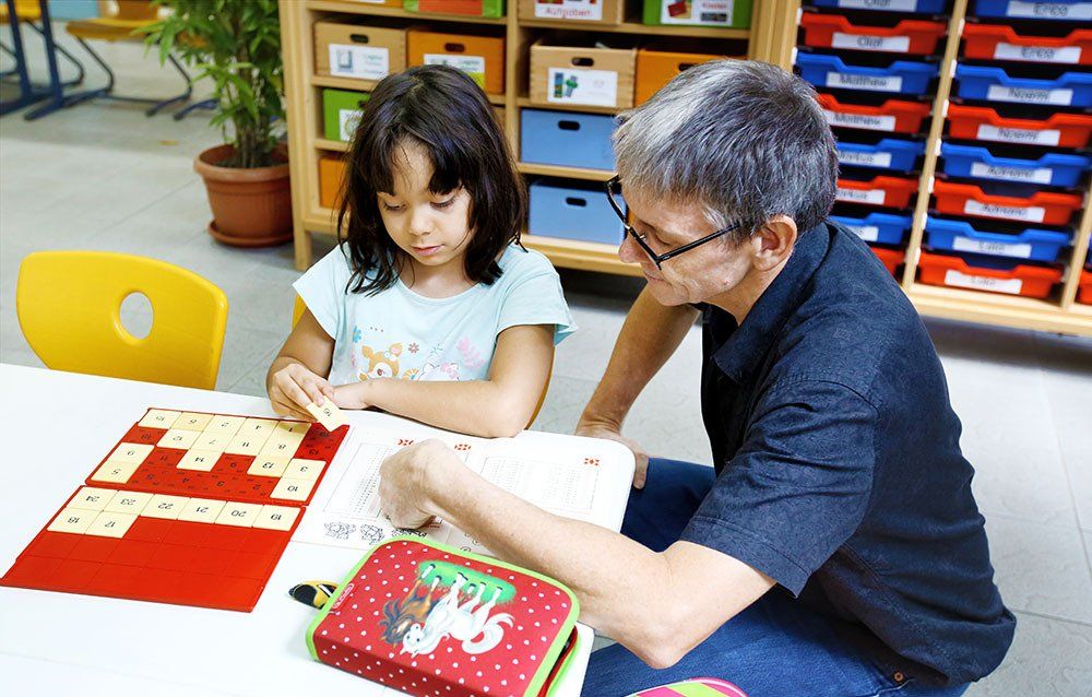 A man is helping a little girl with her homework