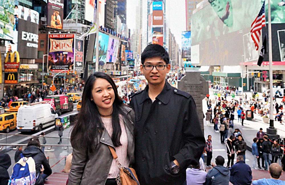 A man and a woman are posing for a picture in front of a crowded city street.