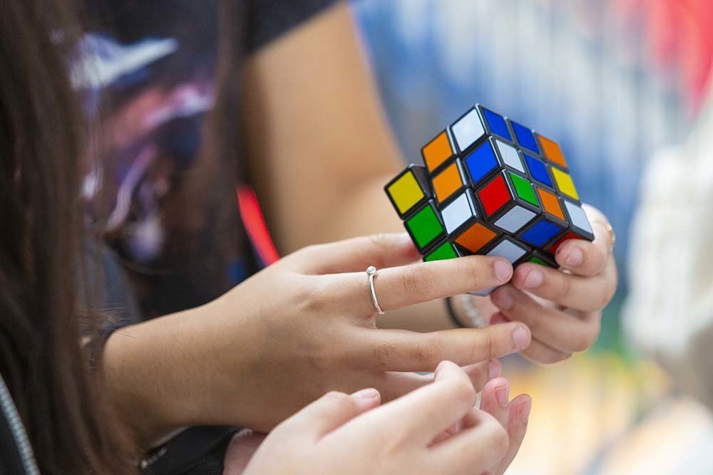 A woman is holding a colorful rubik 's cube in her hands.