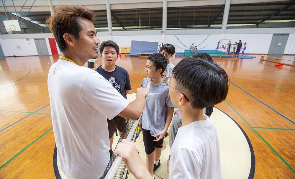 A group of young men are standing in a gym talking to each other.