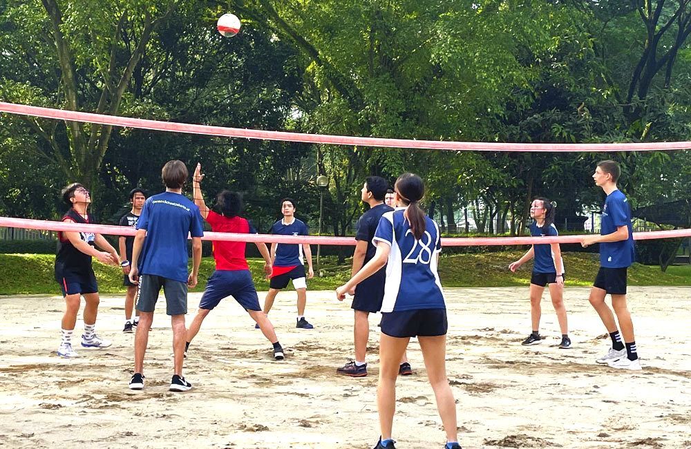 A group of young people are playing volleyball in a park.