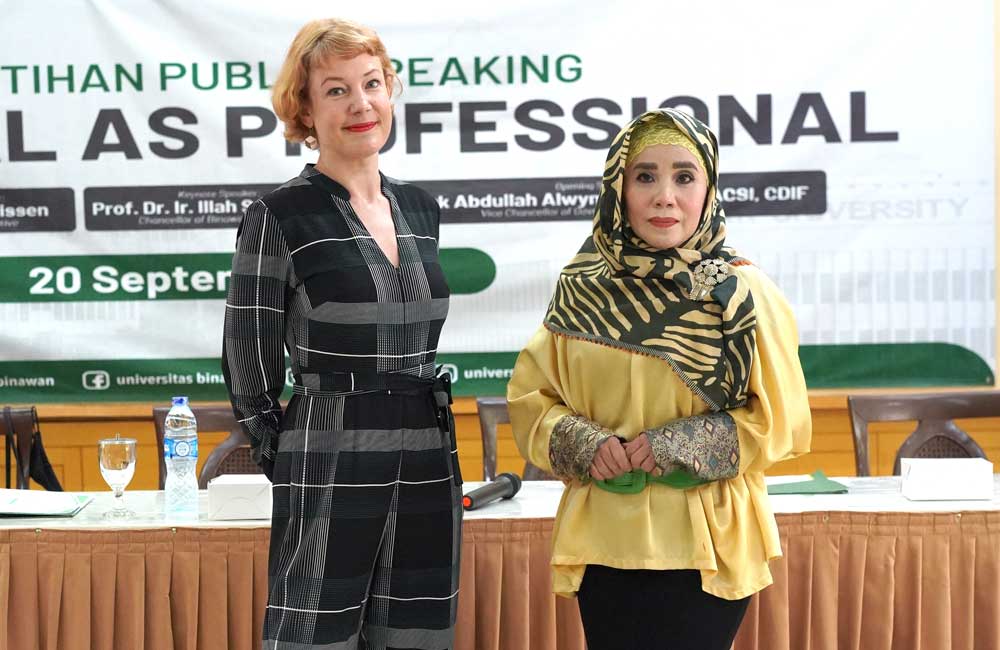 Two women are standing next to each other in front of a sign that says tahan public speaking professional