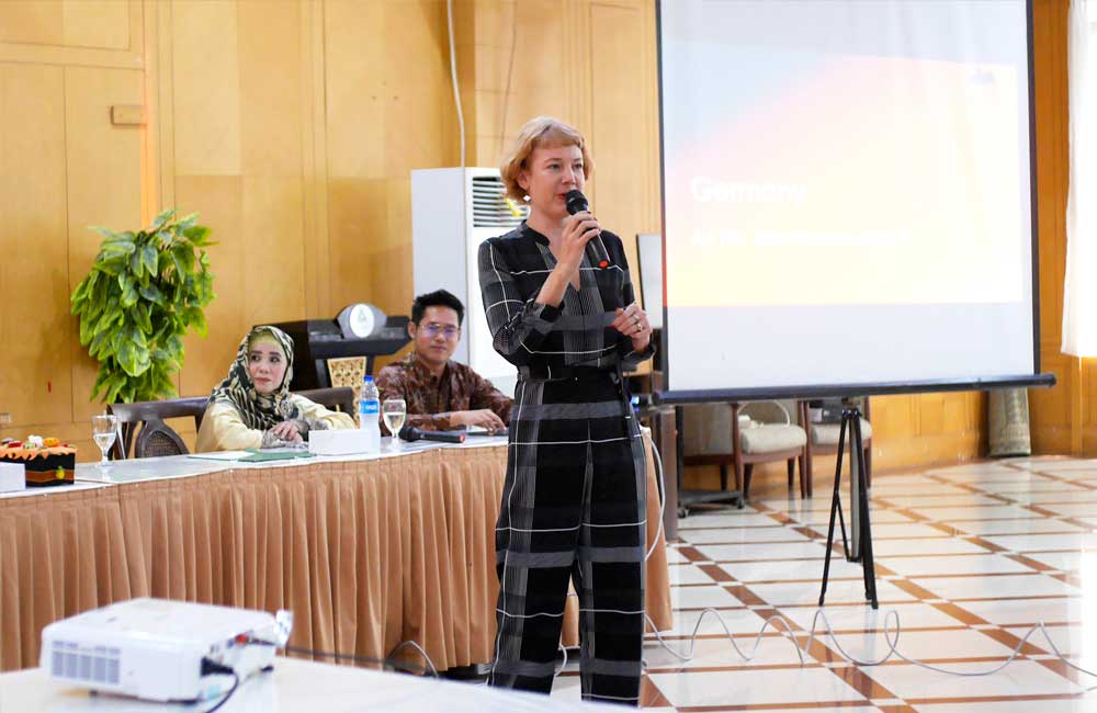 A woman is giving a presentation in front of a projector screen.
