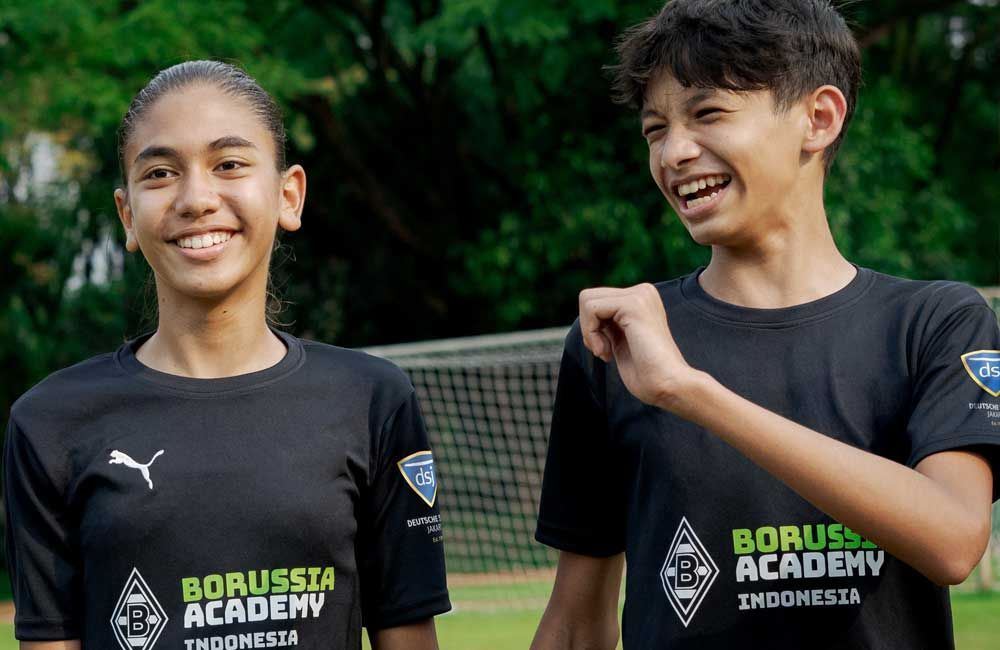 A boy and a girl are standing next to each other on a soccer field.
