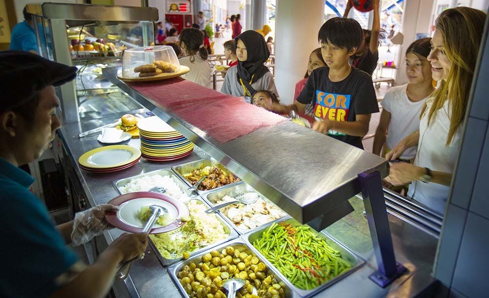 A group of people are standing at a buffet line in a restaurant.