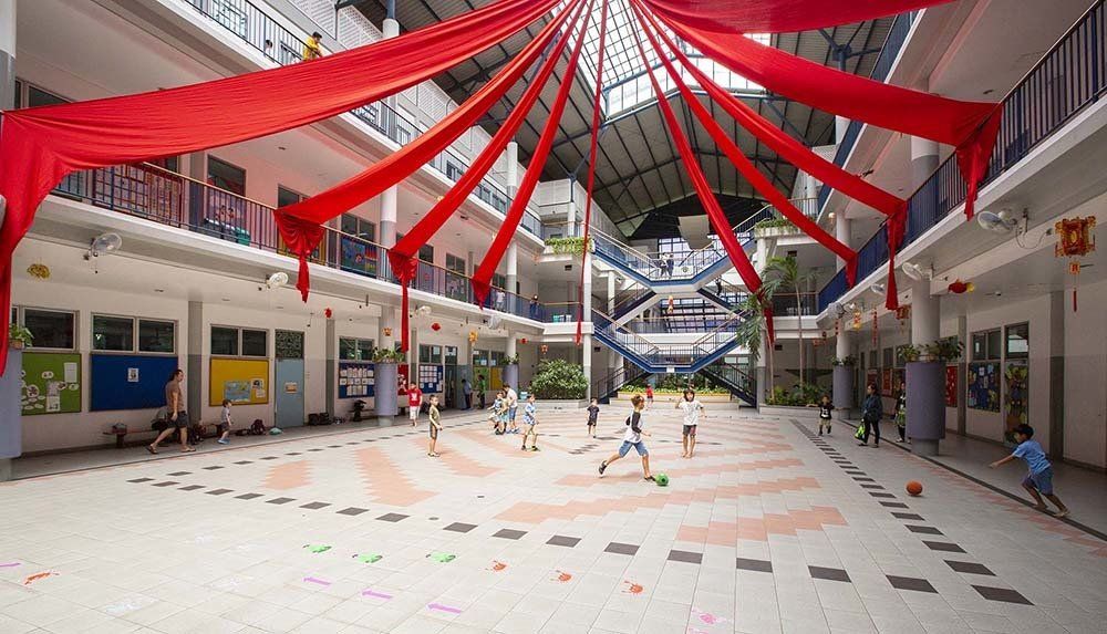 A group of children are playing soccer in a large courtyard.