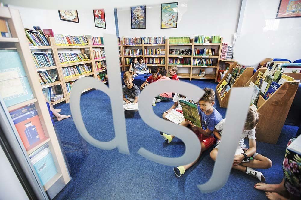A group of children are sitting on the floor in a library reading books