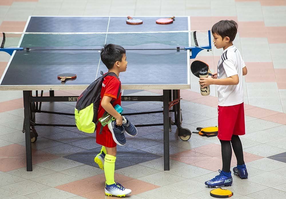 Two young boys are playing ping pong on a table.
