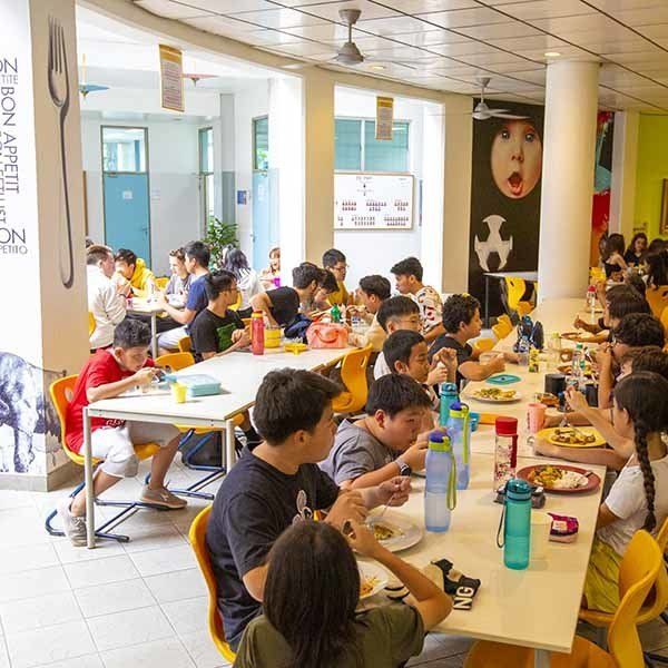 A large group of people are sitting at long tables eating food