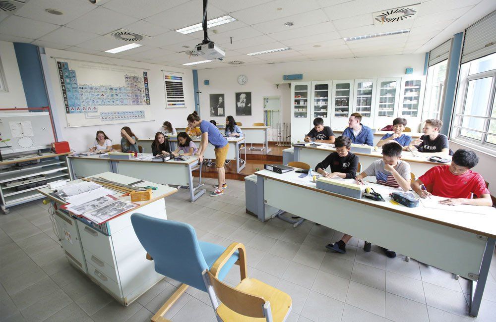 A group of people are sitting at desks in a classroom.
