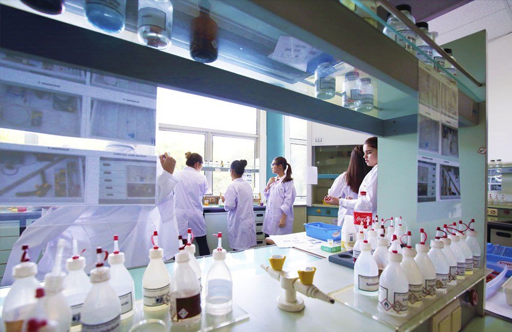 A group of people are working in a lab with bottles of liquid on the table.